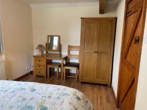 a bedroom with a bed and a desk with a mirror at Tupenny Cottage, Old Mill Farm, Cotswold Water Park in Cirencester