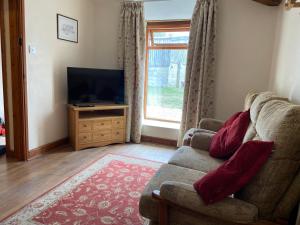 a living room with a couch and a television at Tupenny Cottage, Old Mill Farm, Cotswold Water Park in Cirencester