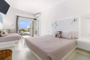 a white bedroom with a bed and a balcony at Manolia View Mykonos in Tourlos