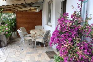 een patio met paarse bloemen en een tafel en stoelen bij Apartmani Zeleni Raj in Dramalj