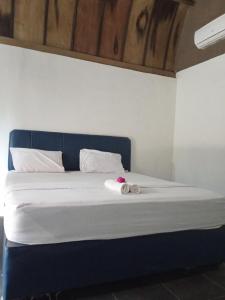 Oda Bungalows في غيلي تراوانغان: سرير مع اللوح الأمامي الأزرق مع وجود منشفة عليه