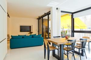 een woonkamer met een blauwe bank en een tafel bij SHELTER in Elegant 2BR with Veranda close to Beach by FeelHome in Tel Aviv