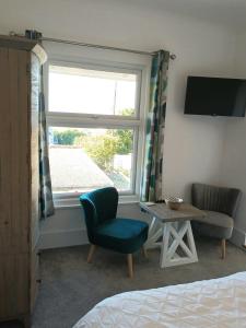 ein Schlafzimmer mit einem Fenster, einem Stuhl und einem Tisch in der Unterkunft Contemporary one bed studio. Sea views and parking in Westward Ho