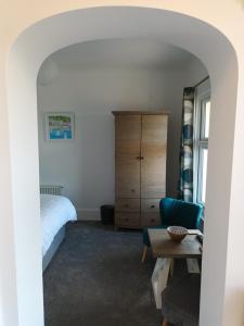 een slaapkamer met een bed, een dressoir en een tafel bij Contemporary one bed studio. Sea views and parking in Westward Ho
