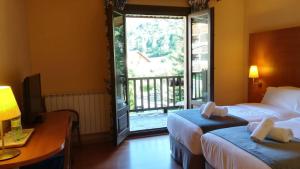 a hotel room with two beds and a large window at Hotel Saurat in Espot