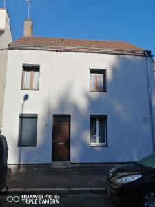 a white house with a brown door and windows at Studio bleu tout équipé avec wifi in Le Creusot