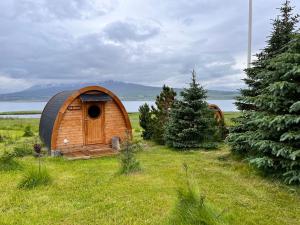 a small wooden hobbit house in a field with trees at Helgafell retreat center in Akureyri