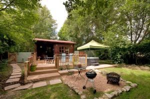 a backyard with a barbecue grill and a cabin at The Lodge with hot tub in Maidstone