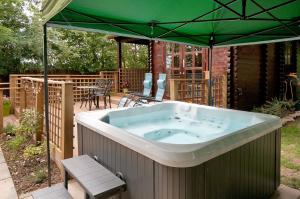 eine große Badewanne unter einem grünen Sonnenschirm in der Unterkunft The Lodge with hot tub in Maidstone