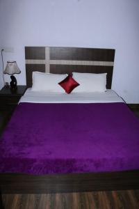 a bed with a purple blanket on top of it at D signature Homestay By Lexstays in Kushālnagar