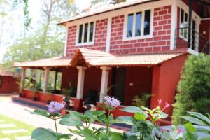 a red house with flowers in front of it at D signature Homestay By Lexstays in Kushālnagar