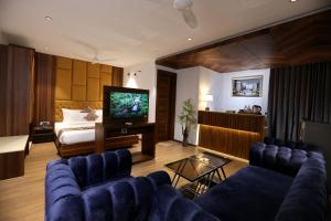 a living room with a couch and a tv and a bed at ROYAL LALIT Grand Hotel in Karnal