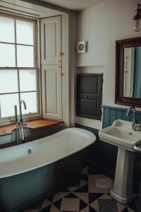 a bathroom with a bath tub and a sink at Custom House Hotel in Bowling