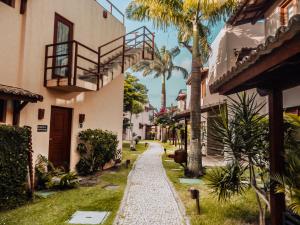 a walkway between two buildings with palm trees at A - Pipa Beleza Unidades Particulares in Pipa