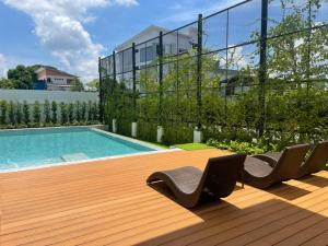 una piscina con sillas en una terraza de madera en Hotel Agnes, en Buriram