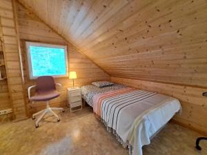 um quarto num chalé de madeira com uma cama e uma cadeira em Villa Tohonnokka em Kalajoki