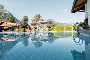 uma piscina com cadeiras e guarda-sóis em Hotel Karlwirt em Pertisau