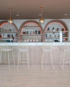 a restaurant with a bar with white stools at Hotel Agnes in Buriram