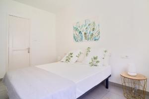 Dormitorio blanco con cama blanca y pintura en la pared en Villa Rosita Suites en Playa de la Malagueta con terraza, en Málaga