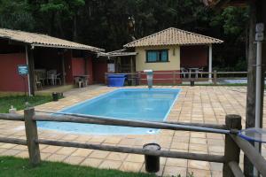 a swimming pool with a fence and a house at Pousada Marumbe in Macacos