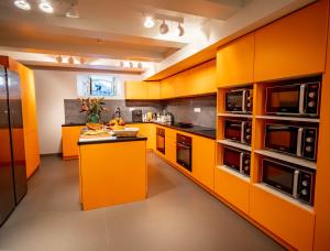 カンヌにあるBANANA'S CAMPのオレンジ色のキッチン(黒の電化製品、キャビネット付)