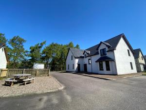 a white house with a picnic table in front of it at Nevis Croft Apartment 3 in Fort William