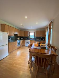 a kitchen with a wooden table and a white refrigerator at Nevis Croft Apartment 3 in Fort William