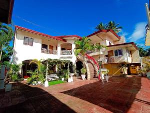 a large white house with palm trees in front of it at Ladolcevita Inland Resort in Cabadbaran