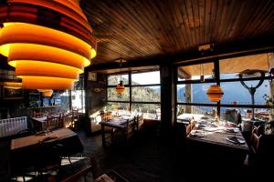 un restaurante con mesas, sillas y ventanas grandes en Balcon del Pirineo Rural Ordesa, en Buesa