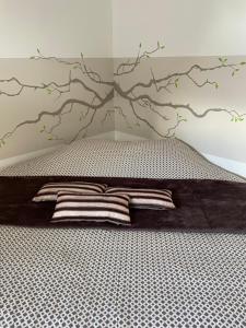 a bed with a tree mural on the wall at Chambres privées chez le particulier aéroport Lille Lesquin in Lesquin