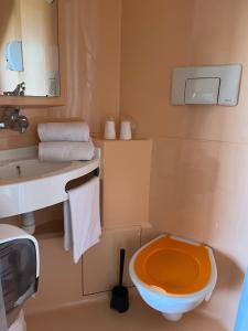 La salle de bains est pourvue de toilettes orange et d'un lavabo. dans l'établissement Première Classe Chateauroux - Saint Maur, à Saint-Maur