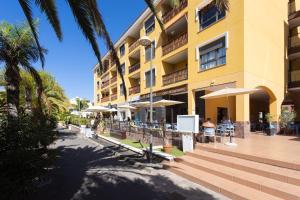 a large yellow building with tables and umbrellas at Palm Mar Studio Apartment in Palm-Mar