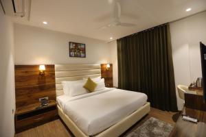 a bedroom with a white bed and a television at ROYAL LALIT Grand Hotel in Karnal