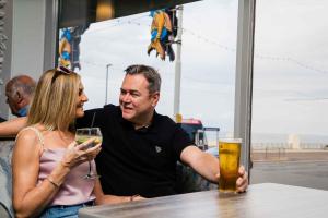 um homem e uma mulher sentados numa mesa com copos de cerveja em Claremont Hotel em Blackpool