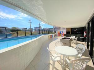 un patio con mesas y sillas y una piscina en Apartamento novinho 2 quartos Ponta Verde, en Maceió