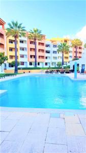 une grande piscine avec des palmiers et des bâtiments dans l'établissement Home Sweet Home, à Albufeira