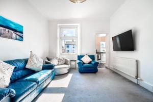 a living room with a blue couch and a tv at Kali Apartment - Spacious 3 bed apartment in Wishaw in Wishaw