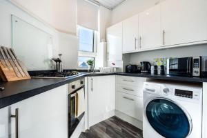 a white kitchen with a washing machine in it at Kali Apartment - Spacious 3 bed apartment in Wishaw in Wishaw