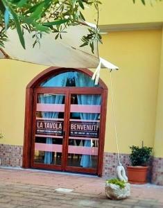 Una puerta a un edificio con un cartel. en LA Tavola Ristorante Pizzeria Da Rino & Figli, en Villaspeciosa