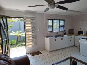 a kitchen with white cabinets and a ceiling fan at Bujumbura Guest House in Port Edward