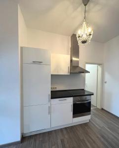 a kitchen with white cabinets and a chandelier at AMS Appartement Spaichingen in Spaichingen