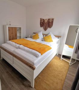 - une chambre avec un grand lit blanc et des oreillers jaunes dans l'établissement AMS Appartement Spaichingen, à Spaichingen