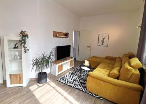 a living room with a yellow couch and a television at AMS Appartement Spaichingen in Spaichingen