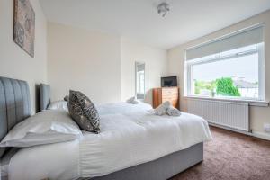 a bedroom with a large white bed and a window at Millfield House - Cosy 2 bed house in Motherwell in Motherwell