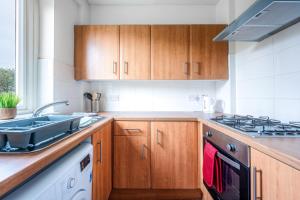 a kitchen with wooden cabinets and a sink at Millfield House - Cosy 2 bed house in Motherwell in Motherwell