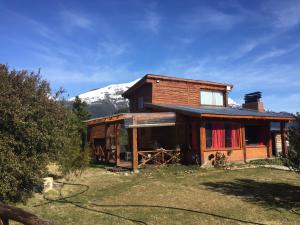 a log cabin with a snow covered mountain in the background at Cabaña Fer in Los Cipreses