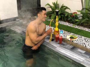ホイアンにあるPHỐ CHỢ ĐÊM Villaの水泳に立って飲み物を飲む男