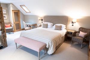 a bedroom with a large bed and two chairs at The Bell at Ramsbury in Marlborough