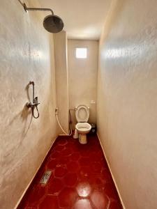 baño con aseo y suelo rojo en Cozy Surf House en Taghazout