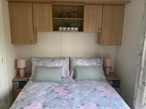 a bedroom with a bed with pink flowers on it at Lili-anns Retreat Cosy Holiday Home in Millom